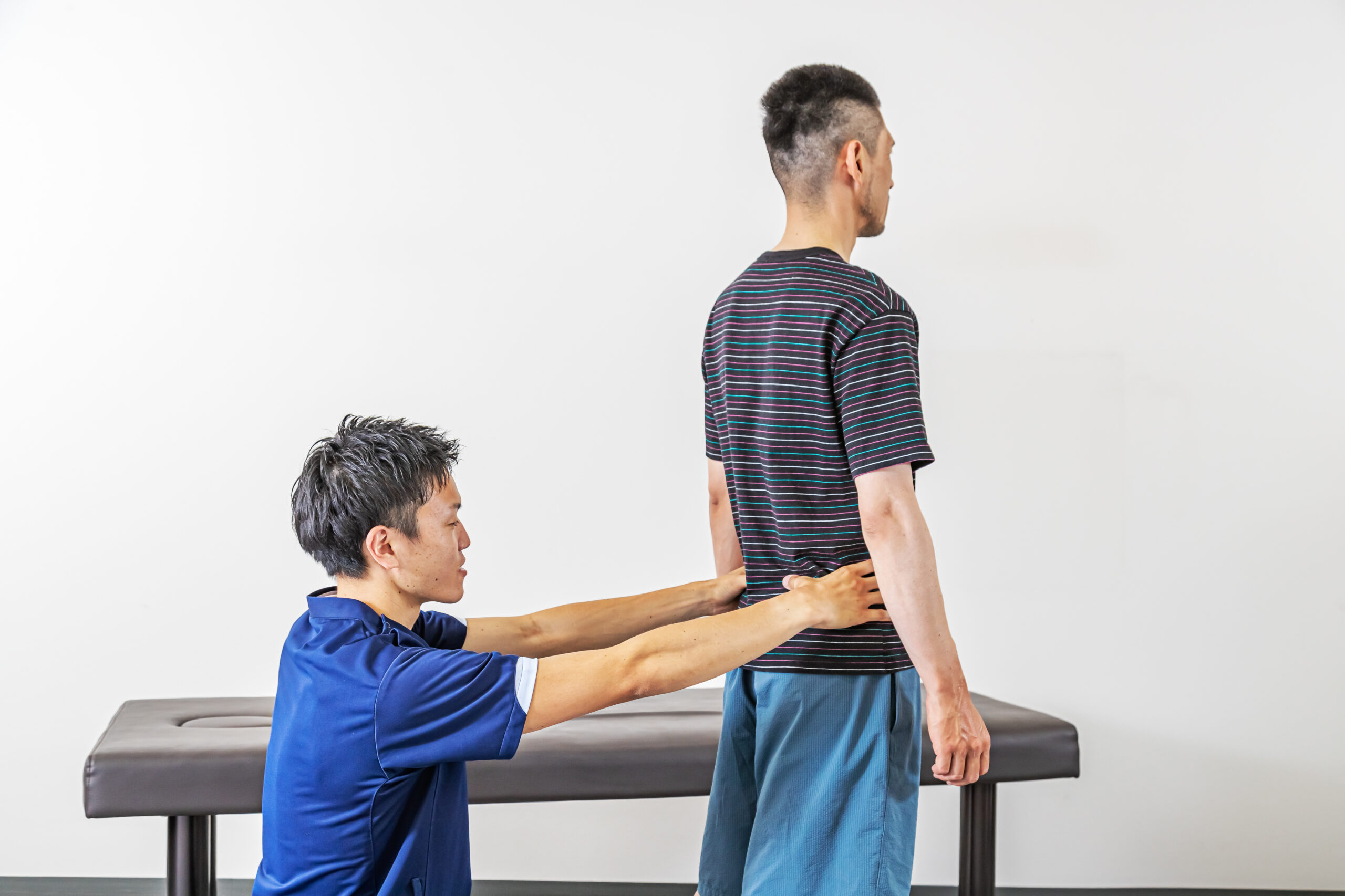 神川さんの腰まわりを触診し、仙腸関節のはまり具合をチェックして腰痛の原因を探る町田先生